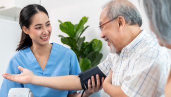 An elderly man having a blood pressure check by his personal caregiver