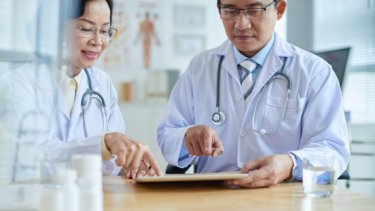Two asian doctors reviewing data on a tablet in a modern medical office