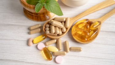 Various medicines and pills in a wooden spoon