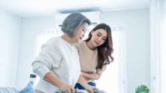 Caregiver aiding elderly woman using walker