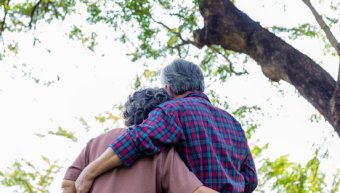 Elderly couple embracing under a tree
