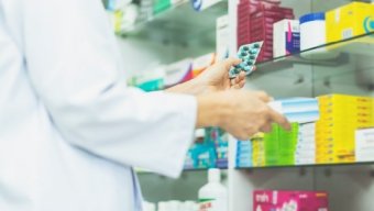 A pharmacist in a pharmacy shop, holding medicines